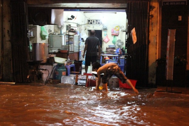 Tại đường Trần Bình, Hồ Tùng Mậu nước ngập tràn vào cả nhà. Người dân cố gắng chặn dòng nước.