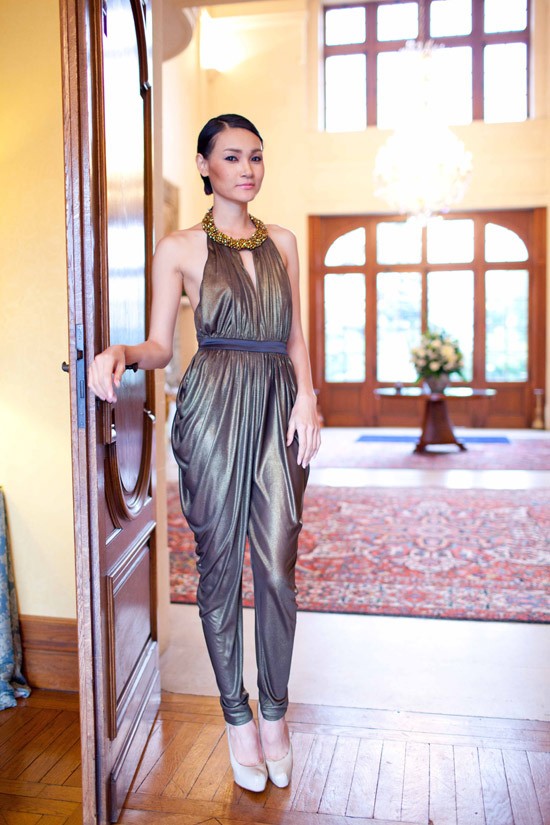 Thùy Trang Next Top diện mẫu jumpsuits ánh kim của Chung Thanh Phong. Trên nền chất vải bóng metallic, những đường xếp được tận dụng để tạo vòng hông và giảm độ bắt sáng.