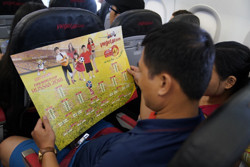 Một hành khách trên tàu bay chăm chú xem lịch thi đấu World Cup 2018 trên bộ lịch thi đấu của Vietjet tặng. Ảnh: Vietjet