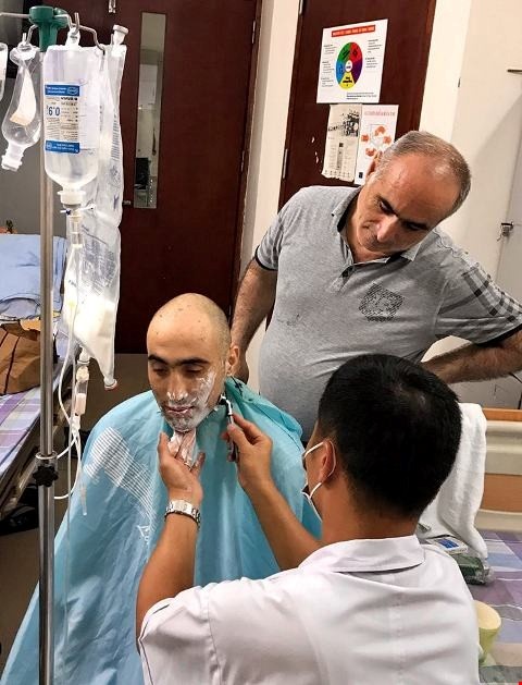 Hình ảnh bác sĩ Viện huyết học và Truyền máu Trung ương cắt tóc, cạo râu cho bệnh nhân Azerbaizan điều trị tại viện.