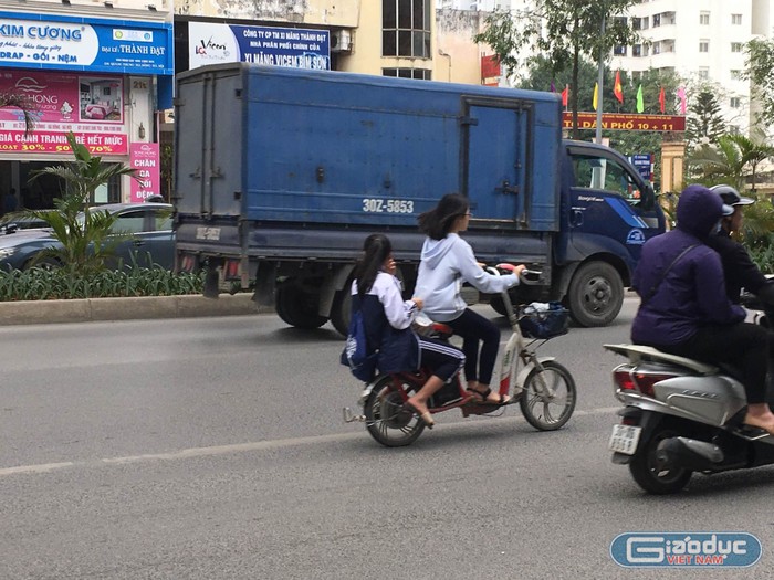 Hai học sinh đi xe máy điện không đội mũ bảo hiểm trên đường Quang Trung, quận Hà Đông.