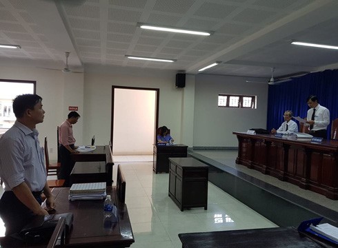 Ông Hồ Văn Lương (phía xa hình) và đại diện ủy quyền của bị đơn đứng nghe tòa tuyên án (ảnh: P.L)
