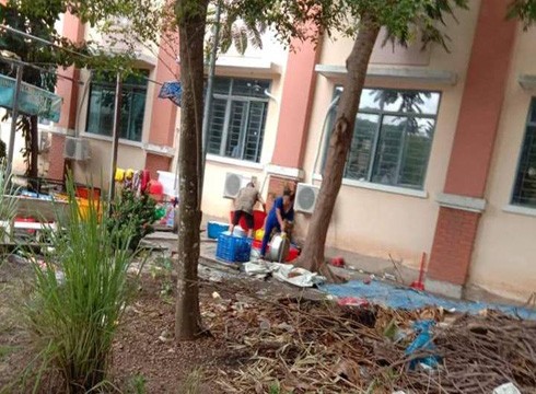 Nhân viên căn tin rửa các dụng cụ, khay thức ăn ở ngay sát bên lớp học (ảnh: CTV)