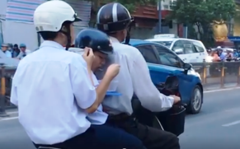 Hai nam sinh vội vàng xúc cơm ăn ngay trên xe gắn máy khi được người thân chở đi học thêm (ảnh từ clip)