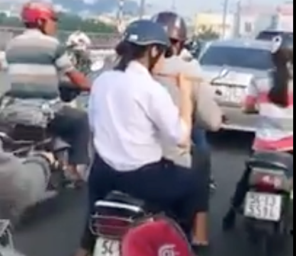 Nữ sinh ăn vội vàng mì ly ngay trên xe gắn máy khi được người thân chở đi học (ảnh cắt từ video clip)