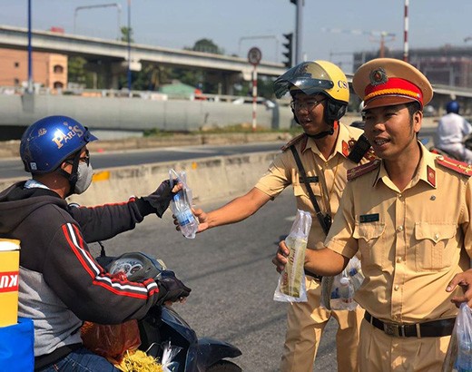 Cảnh sát giao thông Rạch Chiếc phát nước suối, khăn lạnh miễn phí cho người dân về quê ăn tết (ảnh: P.L)