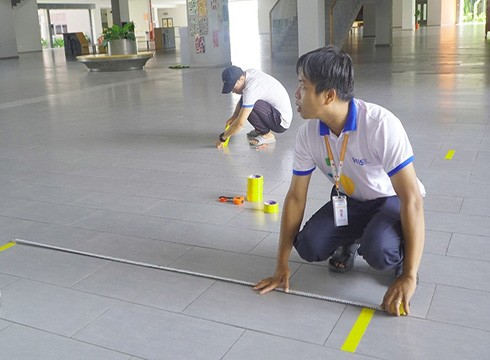Nhân viên trường đang vẽ vạch khoảng cách để phụ huynh và học sinh đứng đảm bảo an toàn (ảnh: VFIS)