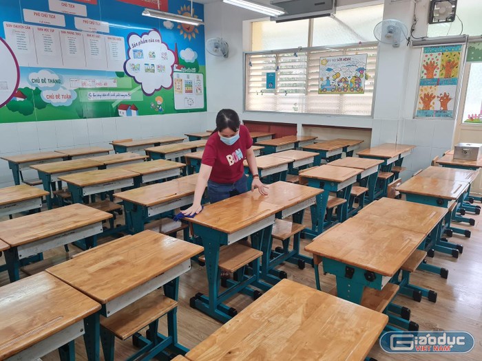 Nhân viên trường tiểu học Nguyễn Bỉnh Khiêm vệ sinh bàn ghế đón học sinh quay lại học (ảnh: P.L)