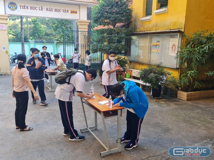 Học sinh lớp 12 trường Trưng Vương khai báo y tế từ ngoài cổng trường (ảnh: P.L)