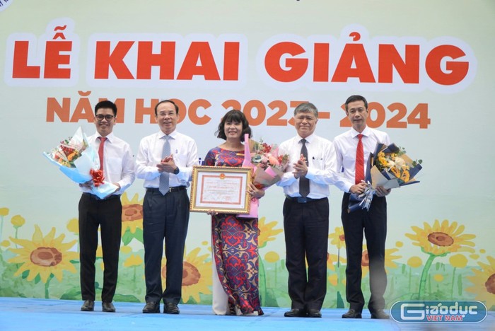 Bí thư Nguyễn Văn Nên (thứ hai, trái sang) trao tặng bằng khen cho lãnh đạo Trường Nguyễn Thị Minh Khai (ảnh: V.D)