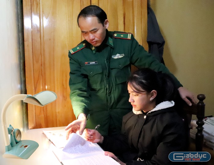 Thiếu tá Ma Đức Minh - Chính trị viên Đồn Biên phòng Phó Bảng hướng dẫn cô con gái út Vàng Thị Chở làm bài tập. Ảnh: Vương Anh.