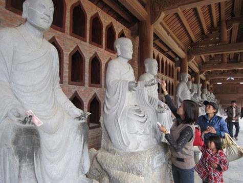 Mặc dù đã có nhắc nhở nhưng người phụ nữ này vẫn đang cố đặt tiền lên tay tượng Phật ở chùa Bái Đính