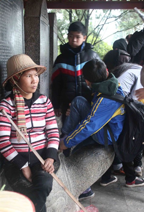 Nhiều người thiếu ý thức còn chọn chỗ ngồi ngay trên mình, đầu rùa trong di tích chùa Hương.