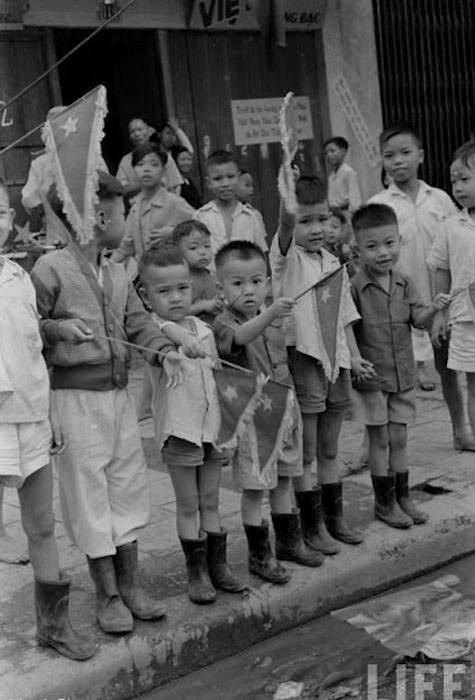 Các cậu bé Hà Nội cùng vẫy cờ chào mừng sự kiện đoàn quân chiến thắng trở về tiếp quản, giải phóng thủ đô, ngày 10/101954.