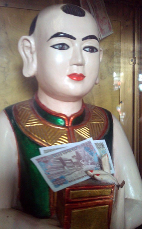 Không chỉ cầm hộp, pho tượng cậu ở Phủ Giầy (Nam Định) còn bị ép cầm cả tiền lẻ.