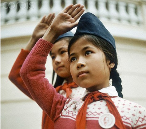 Hai cô bé Hà Nội trong đồng phục mũ ca lô, khăn quàng đỏ, huy hiệu Bác Hồ cùng thực hiện nghi thức chào cờ ở một ngôi trường năm 1973.