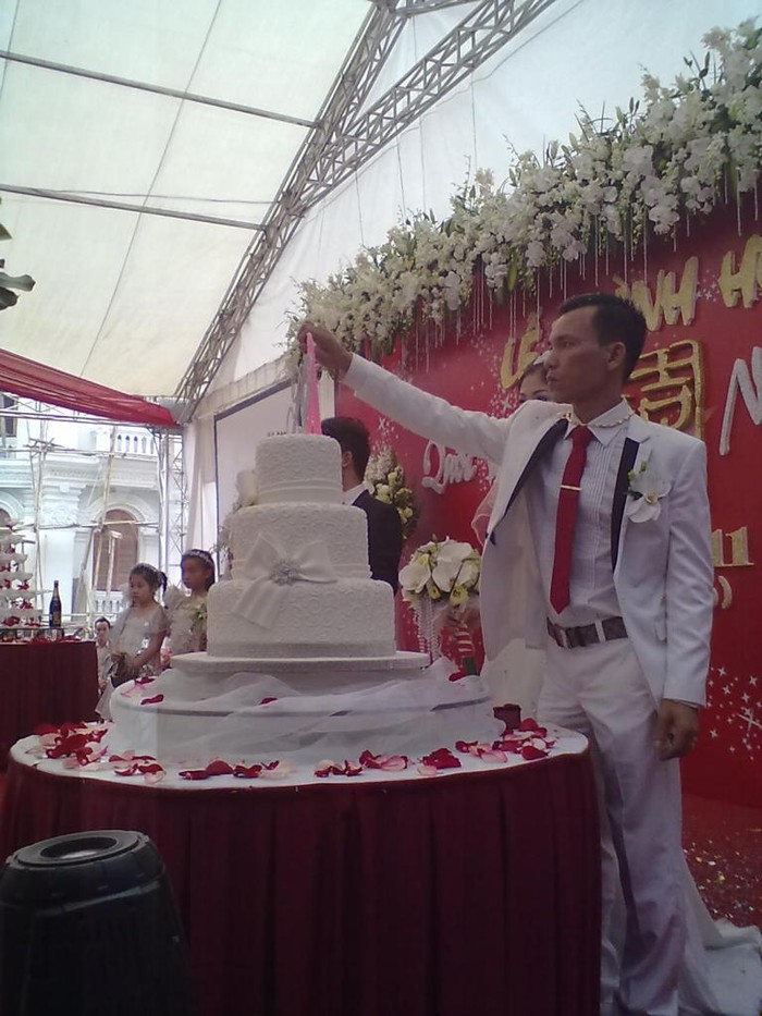 Chú rể Quốc Vương và cô dâu đang châm nến lên bánh ga tô mừng lễ thành hôn.