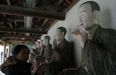 Các pho tượng La Hán ở chùa Mía đều bị "ép" phải cầm tiền lẻ của người đi lễ.