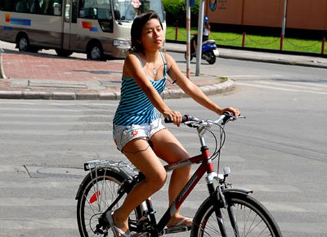 Áo hai dây, quần sooc ngắn đạp xe đạp trên phố.