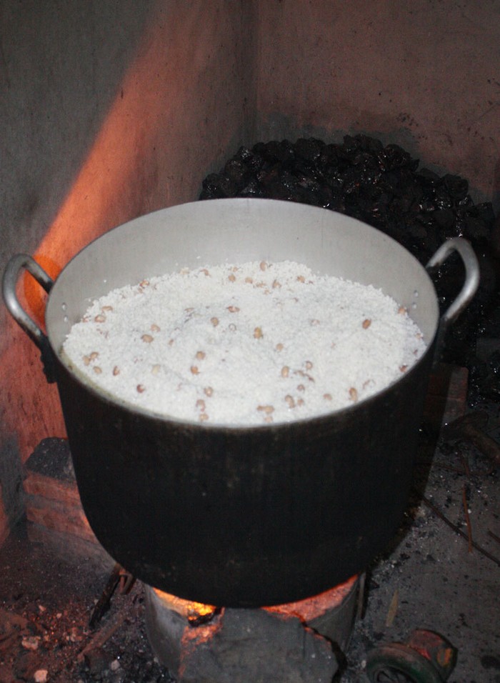 Gạo cho vào xoong, san đều nhưng không được lèn chặt rồi đặt lên bếp lửa đã hồng.