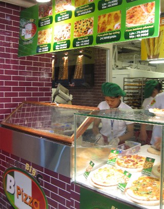 Quầy bánh B-Pizza tại được bố trí đẹp mắt và ấn tượng với trang thiết bị chuyên dụng cùng với đội ngũ thợ bánh lành nghề và chuyên nghiệp, sẵn sàng phục vụ thực khách tại chỗ những chiếc bánh pizza nóng, thơm phức hương vị đặc trưng.