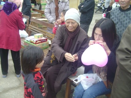 Bà Việt Ly và Sư cô Thích Nữ Như Minh đang cho thổi bóng cho các em nhỏ ở làng phong Quỳnh Lập