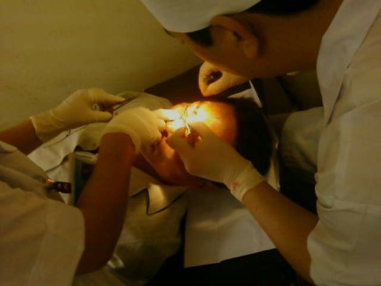 Ông Lê Văn Nam đang được các bác sĩ khâu lại vết thương trên sỗng mũi sau khi bị hành hung