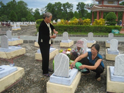Bà Đặng Thị Cháu cùng với hai con bên nấm mộ của liệt sỹ Nguyễn Đình Thực