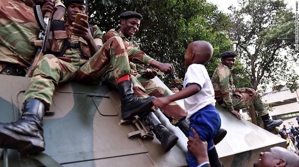 Cậu bé đang vui cùng những binh sĩ bên chiếc xe bọc thép (Ảnh: CNN)