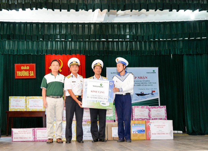 Ông Nguyễn Mạnh Hùng – Ủy viên Ban thường vụ Đảng ủy, Ủy viên Hội đồng quản trị Vietcombank (ngoài cùng bên trái) trao tượng trưng 01 trong 54 thùng quà tặng cho cán bộ, chiến sỹ và nhân dân thị trấn Trường Sa trên đảo Trường Sa.