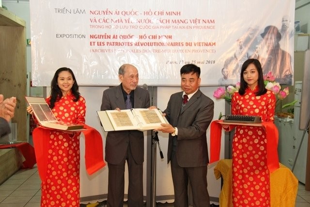 Ông Nguyễn Văn Bổn trao hai cuốn tư liệu sao chép ở Pháp và chiếc máy đánh chữ cho ông Nguyễn Văn Công. Ảnh: Báo Nhân Dân