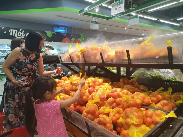 Một bé gái đang học cách chọn cà chua cùng mẹ tại VinMart Times City