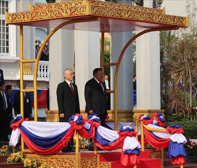 Tổng Bí thư, Chủ tịch nước Lào Bounnhang Vorachith và Tổng Bí thư, Chủ tịch nước Nguyễn Phú Trọng trên bục danh dự, thực hiện nghi thức chào cờ tại Lễ đón. Ảnh: Trí Dũng/TTXVN