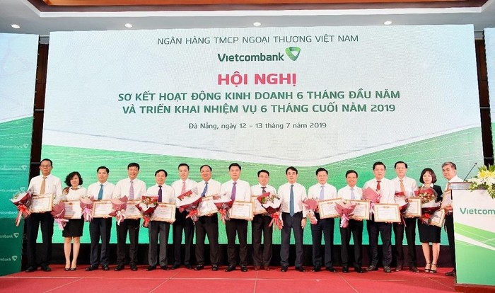 Chủ tịch Hội đồng Quản trị Nghiêm Xuân Thành (thứ 7 từ phải sang) và Tổng giám đốc Phạm Quang Dũng (thứ 6 từ trái sang) trao Giấy khen và tặng hoa cho 14 chi nhánh tiêu biểu trên một số mặt hoạt động 6 tháng đầu năm 2019