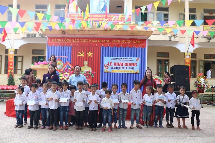 Bà Nguyễn Thị Thu Hà và ông Lê Đình Sơn chụp ảnh lưu niệm với học sinh sau khi phát quà