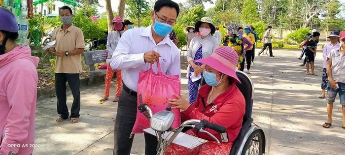 Thầy Lê Văn Chinh, Hiệu trưởng Trường Trung học cơ sở Bưng Riềng phát quà cho người tàn tật tại địa phương