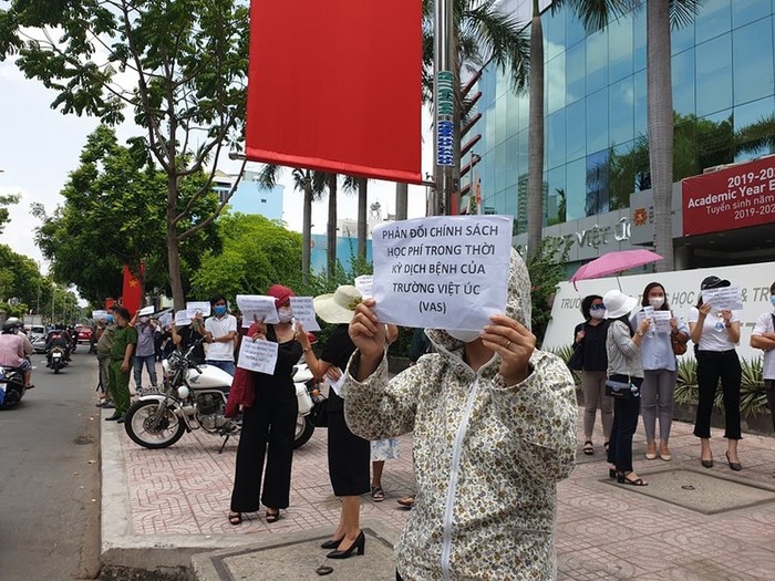 Phụ huynh Trường dân lập Quốc tế Việt Úc (Thành phố Hồ Chí Minh) cầm biểu ngữ đứng trước cổng trường yêu cầu đối thoại với lãnh đạo Trường về vấn đề học phí của học sinh. (Ảnh: baophapluat.vn)