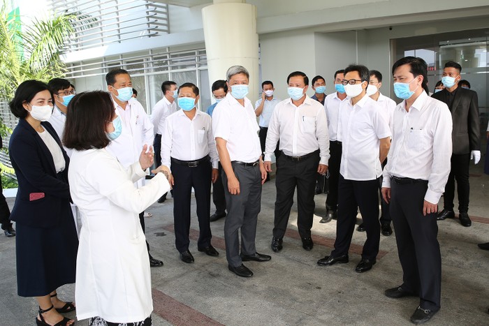 Phó Thủ tướng Vũ Đức Đam ngheo báo cáo quy trình sàng lọc, phân luồng, xử lý trường hợp có triệu chứng sốt, ho, khó thở tại Bệnh viện Sản-Nhi Long An TWG. Ảnh: VGP/Đình Nam