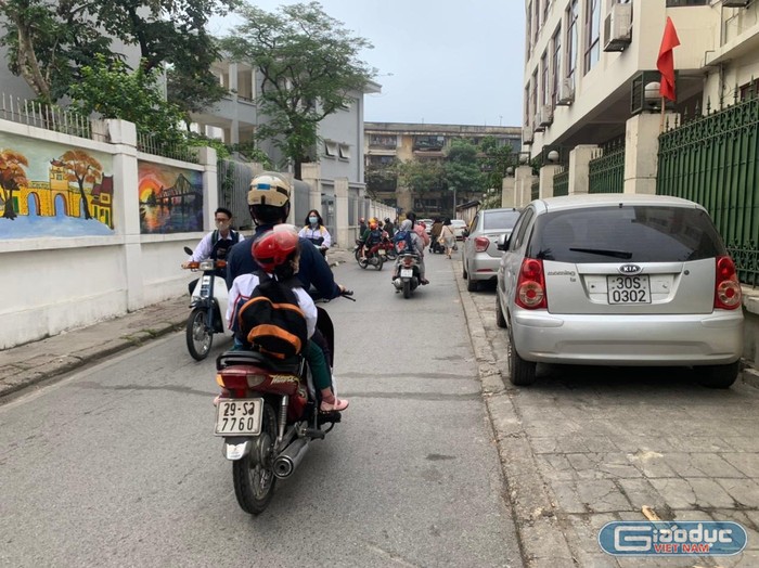 Theo ghi nhận của phóng viên Tạp chí Điện tử Giáo dục Việt Nam, 6h30 sáng, đoạn đường vào Trường Phổ thông Trung học Kim Liên (Đống Đa, Hà Nội) có rất nhiều học sinh đi xe gắn, xe máy điện, xe đạp điện nhưng không đội mũ bảo hiểm. Ảnh: Kim Anh.