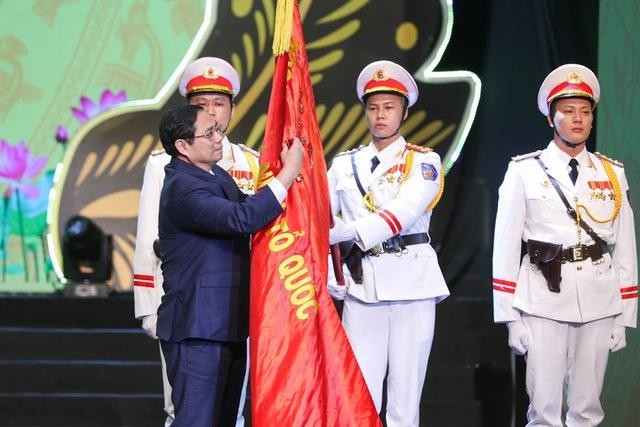 Thủ tướng Phạm Minh Chính gắn Huân chương Hồ Chí Minh lên lá cờ truyền thống của lực lượng Cảnh sát nhân dân - Ảnh: VGP/Nhật Bắc