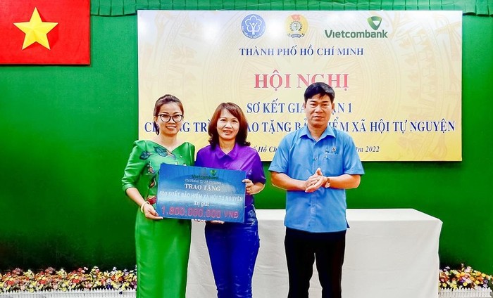 Bà Lê Thị Hòa Bình - Phó Giám đốc Vietcombank Thành phố Hồ Chí Minh (bên trái) trao bảng tượng trưng tái tục bảo hiểm xã hội trị giá 1,8 tỷ đồng cho đại diện đoàn viên các nghiệp đoàn nhận bảo hiểm xã hội năm 2021