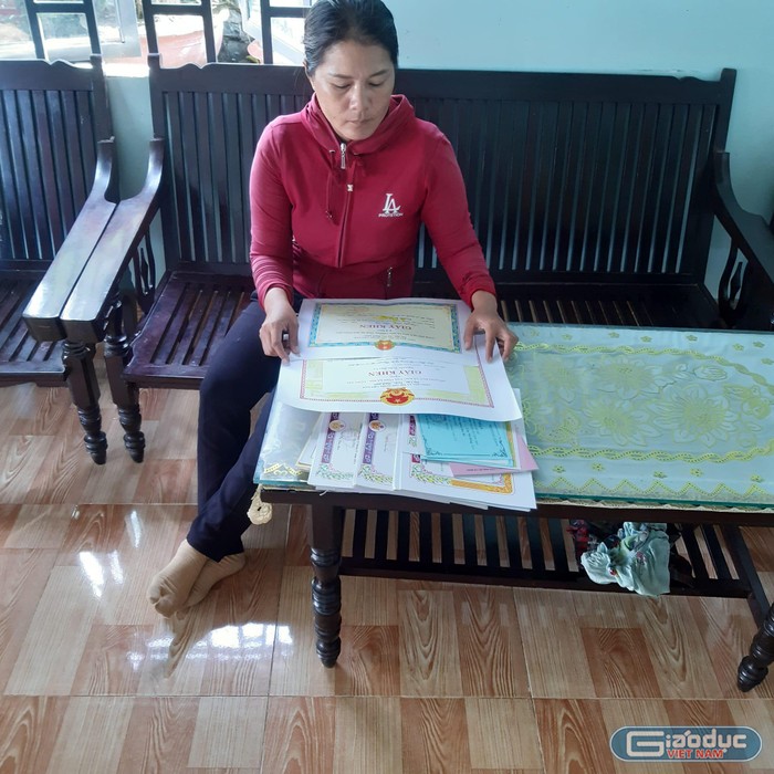 Chị Trần Thị Hồng Vân, mẹ em Nguyễn Trần Bảo Ly, bên bộ sưu tập giấy khen, bằng khen của con gái. Ảnh: Sơn Quang Huyến