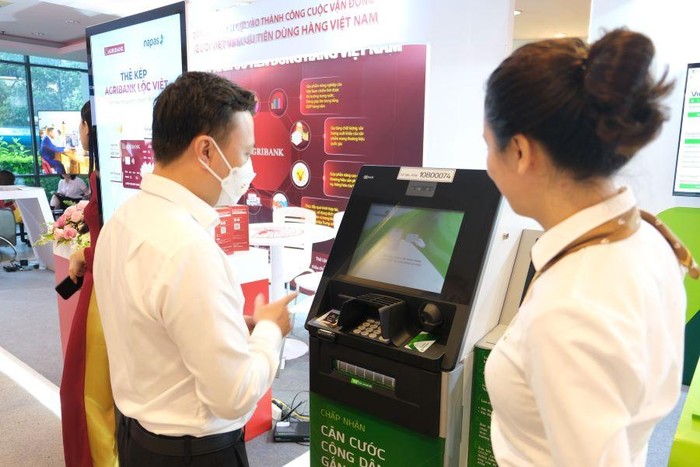 Cán bộ Vietcombank tư vấn khách hàng sử dụng dịch vụ ngân hàng số (ảnh trên) và dịch vụ ATM (ảnh dưới) tại gian hàng trưng bày