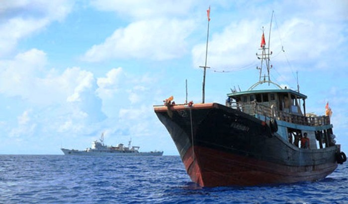 Tàu ngư chính 311 (ở xa) canh cho đội tàu cá đánh bắt trái phép ở Trường Sa