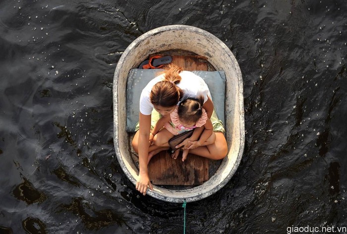 Hai mẹ con người Thái Lan đang ngồi trong một chiếc bồn nhựa được kéo đi trong nước lụt ở Bangkok.