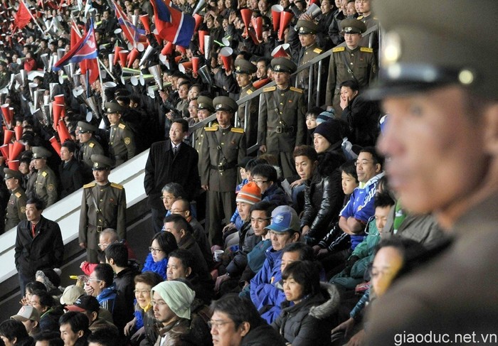 Nhân viên an ninh Triều Tiên giám sát chặt chẽ các cổ động viên của tuyển Nhật Bản (áo xanh).Trong khi đó, phía bên cạnh, các cổ động của đội chủ nhà tha hồ la hét, cổ vũ thoải mái.
