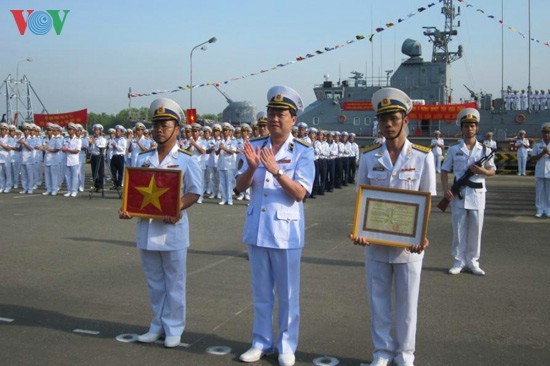 Thuyền trưởng (bên phải) và chính trị viên (bên trái) tàu HQ 272 đón nhận quyết định và Quốc kỳ tại Vùng 2 Hải quân.