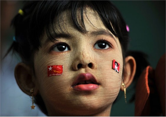 Trong con mắt của những người dân sống cùng khu vực, Myanmar là một quốc gia “hơi khép kín, biệt lập và khó hiểu”. Thậm chí nhiều người còn gắn hình ảnh Myanmar với cảnh hoang tần bởi hậu quả của trận bão Nargis hồi năm 2008 với sự thiệt hại nặng nề về cơ sở vật chất và hơn 140.000 người chết. ảnh: Một cô bé đang đứng đợi sự xuất hiện của nhà lãnh đạo đảng Liên minh Dân chủ Toàn quốc (NLD), bà Aung San Suu Kyi hôm 17/2/2012. Khuôn mặt của cô bé được phủ một lớp bột mặt nạ truyền thống có tên “thanaka” có tác dụng chống nắng và là một thứ mỹ phẩm của phụ nữ Myanmar.