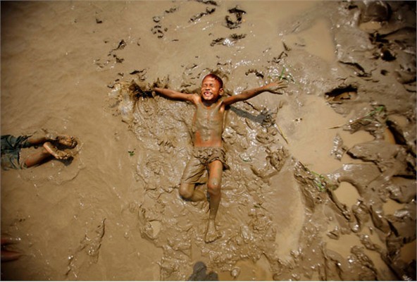 Một cậu bé đang chơi đùa trên vũng bùn ở bờ sông Bago hôm 20/3/2012.