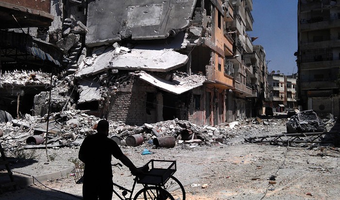 Một người đàn ông Syria đang đứng nhìn khu nhà bị đạn pháo oanh tạc ở Khaldiyeh, Homs, Syria, ngày 11/8,/2012